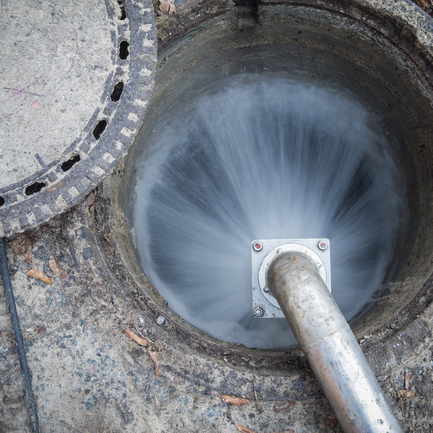 Open sewage channel access with escaping water jet on the mounted high pressure water pipe.